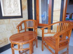 two wooden chairs and a table in front of a window at Ming Homestay in Sidemen