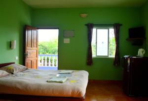 una camera verde con un letto e una finestra di Avalon Inn a Mandrem