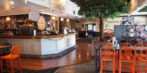a restaurant with a bar with orange chairs at Totara Lodge in Upper Hutt