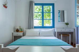 a bedroom with a bed with a blue window at Limnonari Studio in Skopelos Town