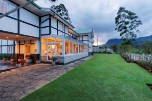 an exterior view of a house with a green lawn at Langdale Boutique Hotel by Amaya in Nuwara Eliya