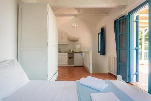 a bedroom with a white bed and a kitchen at Limnonari Split Level Studio in Skopelos Town
