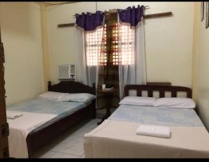 a bedroom with two beds and a window with curtains at COFFEESWINGS LODGING HOUSE in Vigan