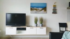einen Fernseher auf einem weißen Schrank im Wohnzimmer in der Unterkunft Strandvakantieappartement Zilverstrand - met binnenzwembad! in De Haan