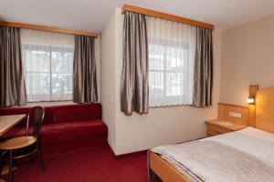 カップルにあるChalet Paznaunのベッドと赤いソファが備わるホテルルームです。