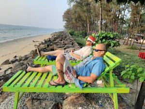 two people sitting on a green bench on the beach at Cherai Ocean View Home in Cherai Beach