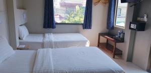 Habitación con 2 camas y ventana en Thapae Gate Lodge, en Chiang Mai