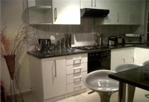 uma cozinha com armários brancos e um forno com placa de fogão em SunSet West Self Catering Maraisburg Roodepoort em Joanesburgo