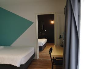 a bedroom with two beds and a desk and a mirror at Résidence Little Sévigné in Rennes