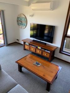 a living room with a flat screen tv and a coffee table at Beachside House in Kingscote
