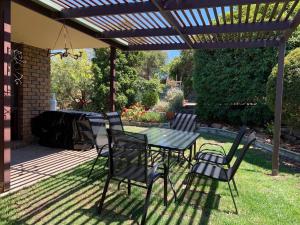 a patio with a table and chairs under a pergola at Beachside House in Kingscote