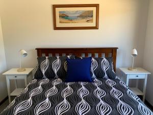 a bedroom with a bed with a blue pillow and two tables at Beachside House in Kingscote