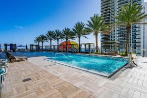 a swimming pool with palm trees and a building at Amazing views on the 29th floor 2BR Beach Resort in Hallandale Beach