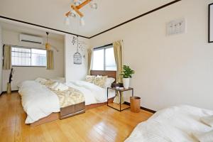 1 dormitorio con 3 camas y ventana en YUZU HOUSE, en Tokio