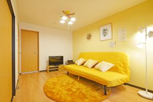 sala de estar con sofá amarillo y TV en YUZU HOUSE, en Tokio