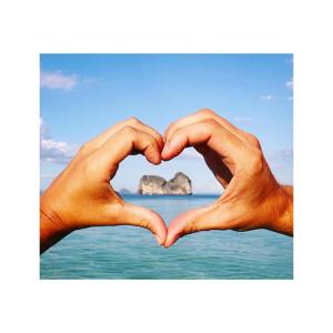 a pair of hands making a heart shape over the ocean at Thanya Beach Resort - SHA Plus in Ko Ngai