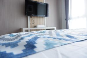 uma cama com um edredão azul e branco e uma televisão em Tiba at Jatinangor Hotel em Cikeruh
