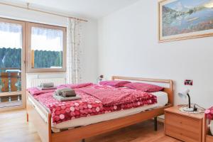 a bedroom with a bed with a red comforter at Cèsa Sot Rodela - Sas Piat in Campitello di Fassa