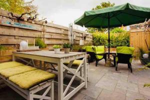 a patio with a table and a green umbrella at Zee-en-Zo Noordwijk in Noordwijk