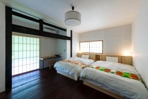 a bedroom with a large bed and a desk at Setouchi Cominca Stays Hiroshima Chojaya in Shōbara