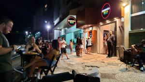 un grupo de personas sentadas fuera de una tienda por la noche en Apartamento Guarapari com simpatia, en Guarapari