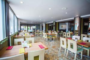 um restaurante com mesas e cadeiras de madeira e janelas em Phuket Merlin Hotel em Cidade Phuket