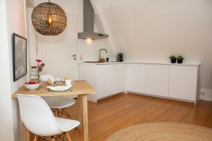a kitchen with white cabinets and a wooden table and chairs at Apartments Waterland in Monnickendam