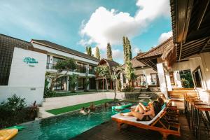 a group of people sitting in chairs by a swimming pool at The Palms Canggu in Canggu