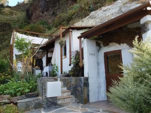 La cueva de Ángel B&B في Firgas: منزل أبيض صغير مع علامة أمامه
