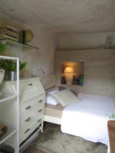a bedroom with a white bed and a dresser at La cueva de Ángel B&B in Firgas