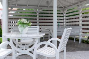 a white table with white chairs and a vase of flowers at Domki Wioska Rybacka in Hel