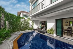 a swimming pool in front of a house at Thaimond Residence by TropicLook in Nai Harn Beach