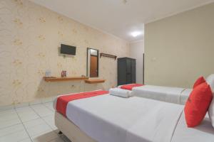 a room with two beds and a tv on the wall at RedDoorz @ Surapati in Bandung