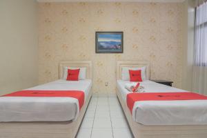 a bedroom with two beds with red pillows at RedDoorz @ Surapati in Bandung