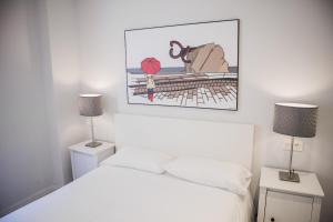 a white bedroom with a bed and two lamps at Plaza B - Local Rentss in San Sebastián