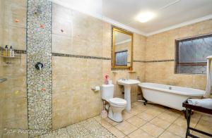 a bathroom with a tub and a toilet and a sink at Mountain Dew Guest House in George +57 photos