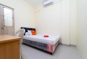 a small bedroom with a bed and a desk at KoolKost Syariah at Green Lake City in Gondrong