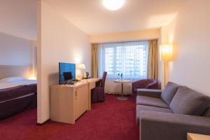 a hotel room with a bed and a couch and a television at Riga Islande Hotel with FREE Parking in Riga