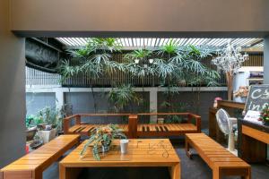 a restaurant with wooden benches and potted plants at Silom Forest Exclusive Residence in Bangkok