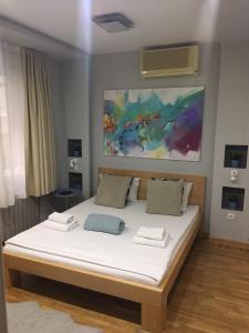 1 dormitorio con 1 cama con sábanas blancas y una pintura en L9 Top Central Rooms and Apartments 2, en Belgrado
