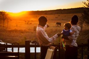 un hombre y una mujer sosteniendo a un niño frente a la puesta de sol en Kololo Game Reserve en Welgevonden Game Reserve