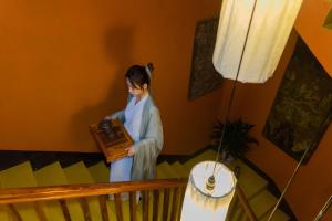 a woman standing in a room holding a radio at Yangshuo Village Inn in Yangshuo