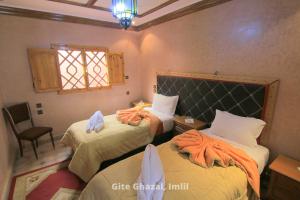 1 dormitorio con 2 camas y toallas. en Gite Ghazal - Atlas Mountains Hotel en Imlil