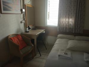 - une chambre avec un lit, un bureau et une chaise dans l'établissement Momo's Hostel, à Tel Aviv
