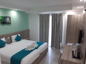 a hotel room with two beds and a television at TJ Boutique in Marsaskala