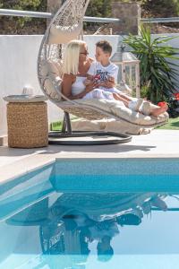 una mujer y un niño sentados en una silla junto a una piscina en Secret Paradise, en Koutsounari