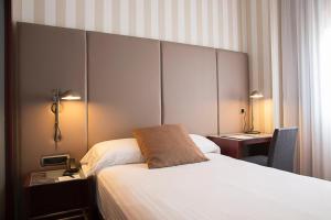 a hotel room with a large bed and a desk at Zenit Valencia in Valencia