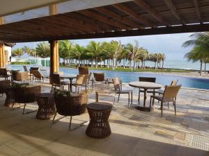 a patio with tables and chairs next to a pool at Beach Place Aquiraz Riviera in Aquiraz