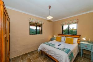 una camera da letto con un letto e due finestre di Vogelsang Farm Cottage a Oudtshoorn