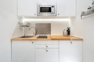 a white kitchen with a sink and a microwave at Cozy Einstein in Berlin